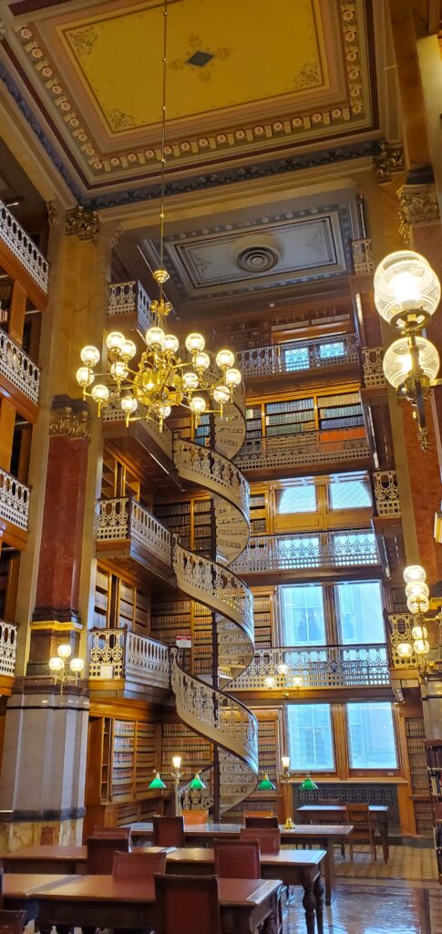 Image of the interior of the State Law Library, featuring spiral staircases and numerous lit lamps and an chandelier.